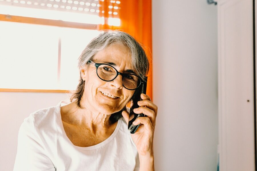 An older woman has a phone in her hand taking a phonecall.